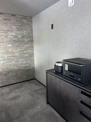 A modern kitchen with a stone wall, a built-in oven, and a dark countertop. - Private villa in Ichinomiya-cho, Chiba, sauna, pool, Jacuzzi (ichinomiyamachiitinomiya)