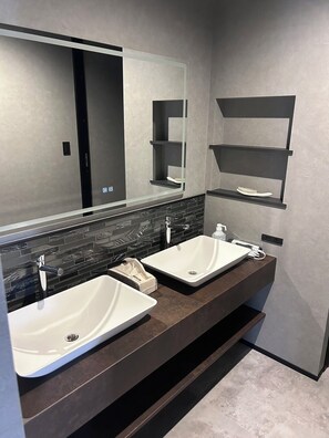 Une salle de bain avec deux lavabos, un grand miroir et des étagères intégrées.