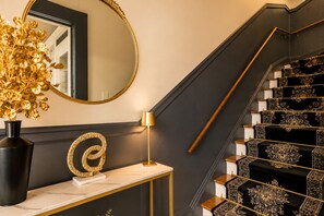 A staircase with ornate black and gold carpeting, a gold-framed mirror, and a gold lamp on a marble console. - Steps from Ghirardelli Square • 4BR with Sauna, Arcade & Private Deck (San Francisco)
