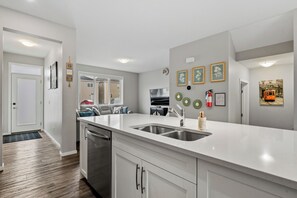 A modern kitchen with a large island, stainless steel appliances, and a view of the living area. - Stay Cool! -Modern 3BR Home Near YYC with New Central AC (Calgary)