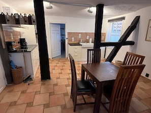 A kitchen with a dining table and chairs, a coffee machine, and a window with blinds. - Grebenstein with castle & towers near Sleeping Beauty's Sababurg & Rapunzel's Trendelburg (Grebenstein)