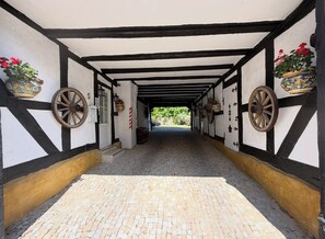 Un pasillo con piso de adoquines, paredes blanco y negro, y ruedas decorativas.
