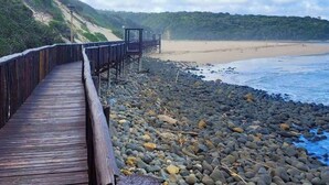 A wooden boardwalk leading to a beach with a rocky shoreline and a clear sky. - Tranquil 1-bedroom Apartment Near Gonubie Beach (East London)