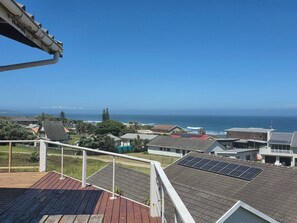Un barrio residencial con casas, una terraza de madera y vista al océano.