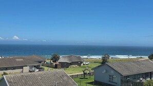 Un quartier résidentiel situé sur la côte, avec des maisons, une vue sur l’océan et un ciel dégagé.