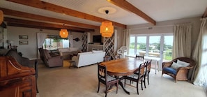 A spacious living area with a wooden dining table, sofas, and wicker chairs. - Serene Coastal Retreat With Private Pool in Amatola (Great Kei)