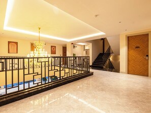 A modern hotel lobby with a marble floor, a decorative railing, a chandelier, and a staircase. - Saltstayz Premier - Sector 28 Faridabad (Faridabad)