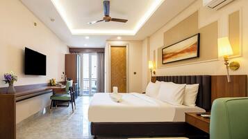 A hotel room with a bed, a desk, a chair, a television, and a ceiling fan.
