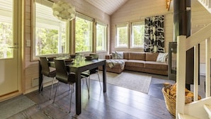 L’intérieur d’un chalet accueillant, avec une table à manger, un canapé et une cheminée.