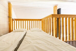 Quarto com cama, paredes de madeira, janela e lareira.