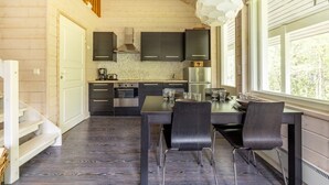 Une cuisine moderne avec des meubles de rangement aux couleurs foncées, une table à manger avec des chaises et une grande fenêtre.