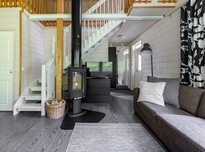 A cozy living room with a fireplace, a sofa, and a staircase.