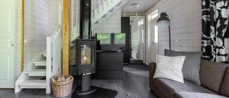 Una sala de estar acogedora con chimenea, un sofá y una escalera.