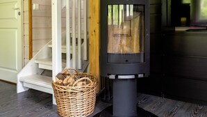 Un poêle à bois, un panier en osier rempli de bois de chauffage et un escalier.