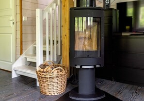 Puuhellaa, rottinkikori täynnä polttopuita ja portaikko.