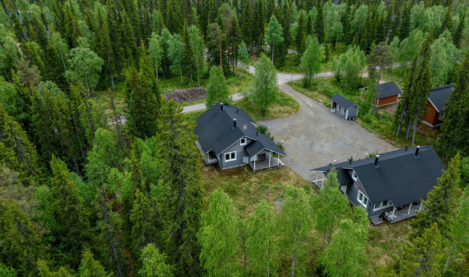 Un quartier résidentiel composé de plusieurs maisons, entouré d’une forêt dense.