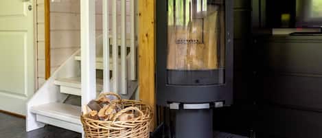 A wood-burning stove, a wicker basket with firewood, and a staircase.