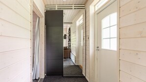 Un couloir aux murs en bois, doté d’un plancher sombre et d’une porte avec une fenêtre.