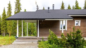 Une cabane dotée d’un porche couvert, d’un revêtement en bois et d’une allée en gravier.