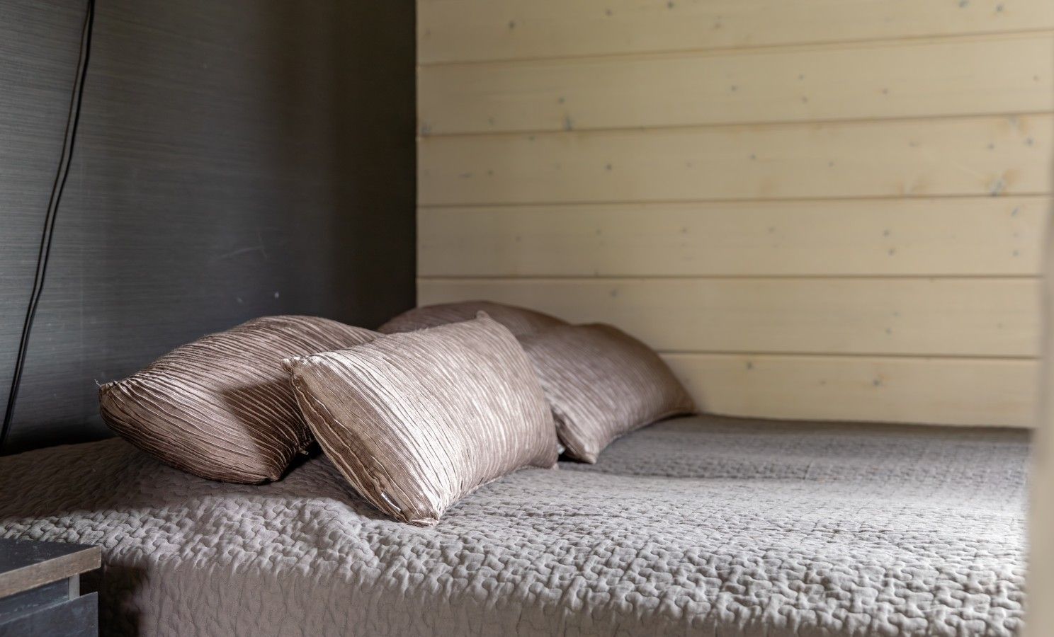Una cama con un edredón texturizado y dos almohadas.