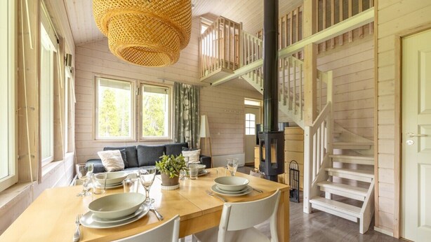 Un coin repas en bois avec une table dressée pour deux personnes, un canapé et un escalier.