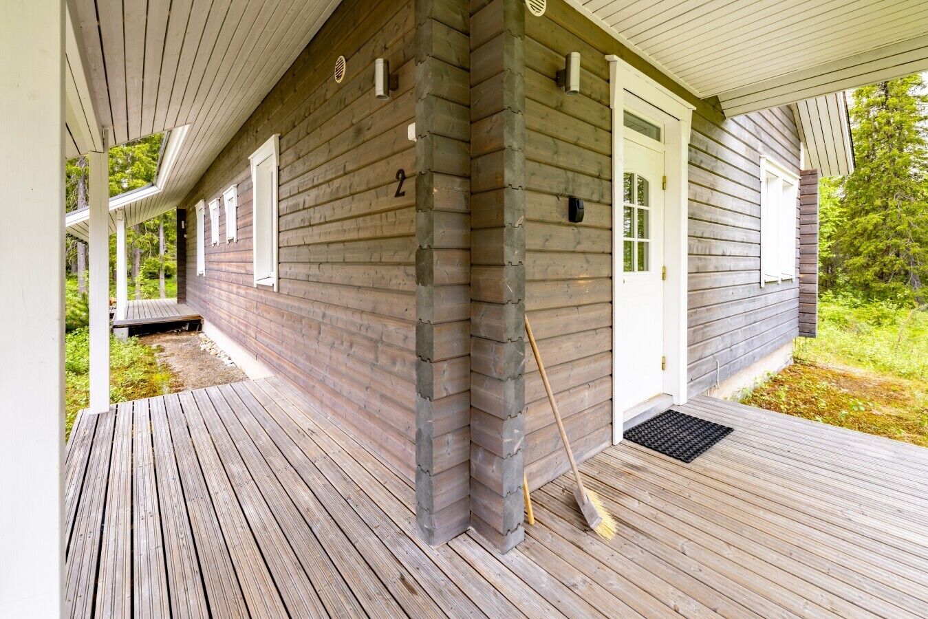 Ett trähus med en veranda, en dörr och ett fönster.