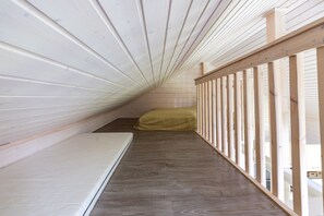 A narrow attic bedroom with a wooden floor, a mattress, and a window with a view. - Villa Lumi 2 | Cozy Arctic Retreat in Ylläs (Ylläsjärvi)