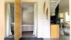 Un intérieur en bois comprenant un lit, un luminaire suspendu et un coin cuisine.