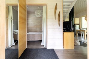 Interior em madeira com cama, luminária pendente e cozinha.