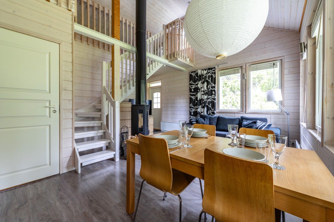 Un espace repas comprenant une table en bois, des chaises et un escalier menant à un niveau supérieur.