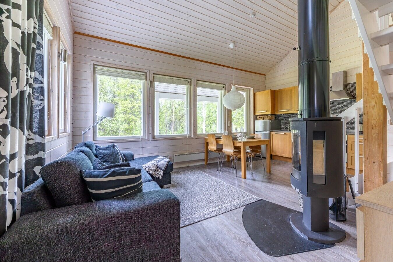 Ett mysigt vardagsrum med en soffa, ett matbord och en vedkamin.