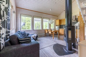 Ein gemütliches Wohnzimmer mit Sofa, Esstisch und Kaminofen.