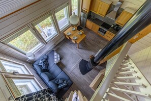 A modern interior with a sofa, dining table, kitchen, and large windows. - Villa Lumi 1 | Cozy Arctic Retreat in Ylläs (Ylläsjärvi)