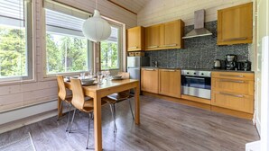 Une cuisine moderne avec des meubles en bois, un four en acier inoxydable et une grande fenêtre donnant sur les arbres.