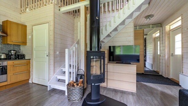 Un intérieur moderne avec un escalier en bois, une cheminée, un coin cuisine et un téléviseur.