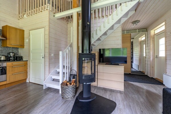 Un intérieur moderne avec un escalier en bois, une cheminée, un coin cuisine et un téléviseur.