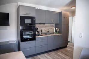 Una cocina moderna con gabinetes grises, horno integrado y microondas.