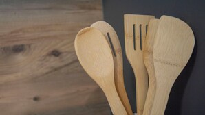 Holzküchenutensilien vor einem dunklen Holzuntergrund.
