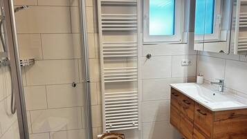 Ein Badezimmer mit Dusche, Toilette, Waschbecken und Spiegel.