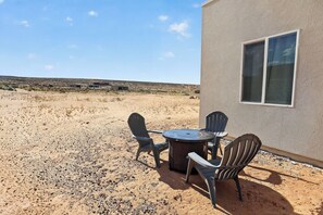 A desert landscape with a building featuring a window and outdoor seating.