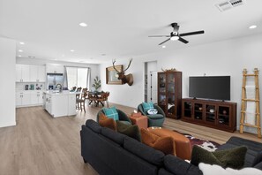 A modern living space with a sofa, TV, and a mounted deer head.