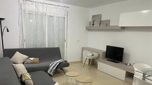 Un soggiorno moderno con un divano, una televisione, un tavolino e una poltrona.