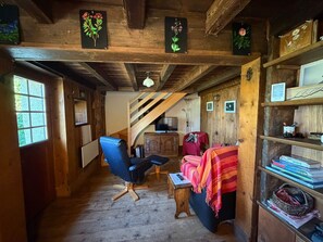 A wooden interior with a chair, a bed, a television, and a bookshelf. - Chalet 1813 Nature & Panorama (Montreux)
