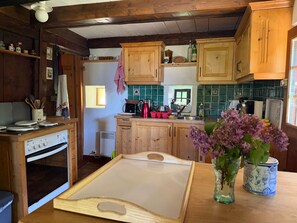 A rustic kitchen with wooden cabinets, a stove, and a window. - Chalet 1813 Nature & Panorama (Montreux)
