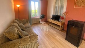 A living room with a sofa, a small table, a television, and a fireplace.