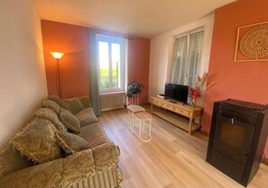 Una sala de estar con sofá, una mesita, televisor y chimenea.