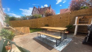 A backyard with a wooden fence, a picnic table, and a barbecue grill.