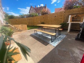 A backyard with a wooden fence, a picnic table, and a barbecue grill.