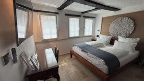A bedroom with a bed, bedside tables, a desk, and a large wall decoration.