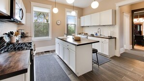 Een moderne keuken met witte kasten, een centraal eiland, een fornuis en hanglampen.